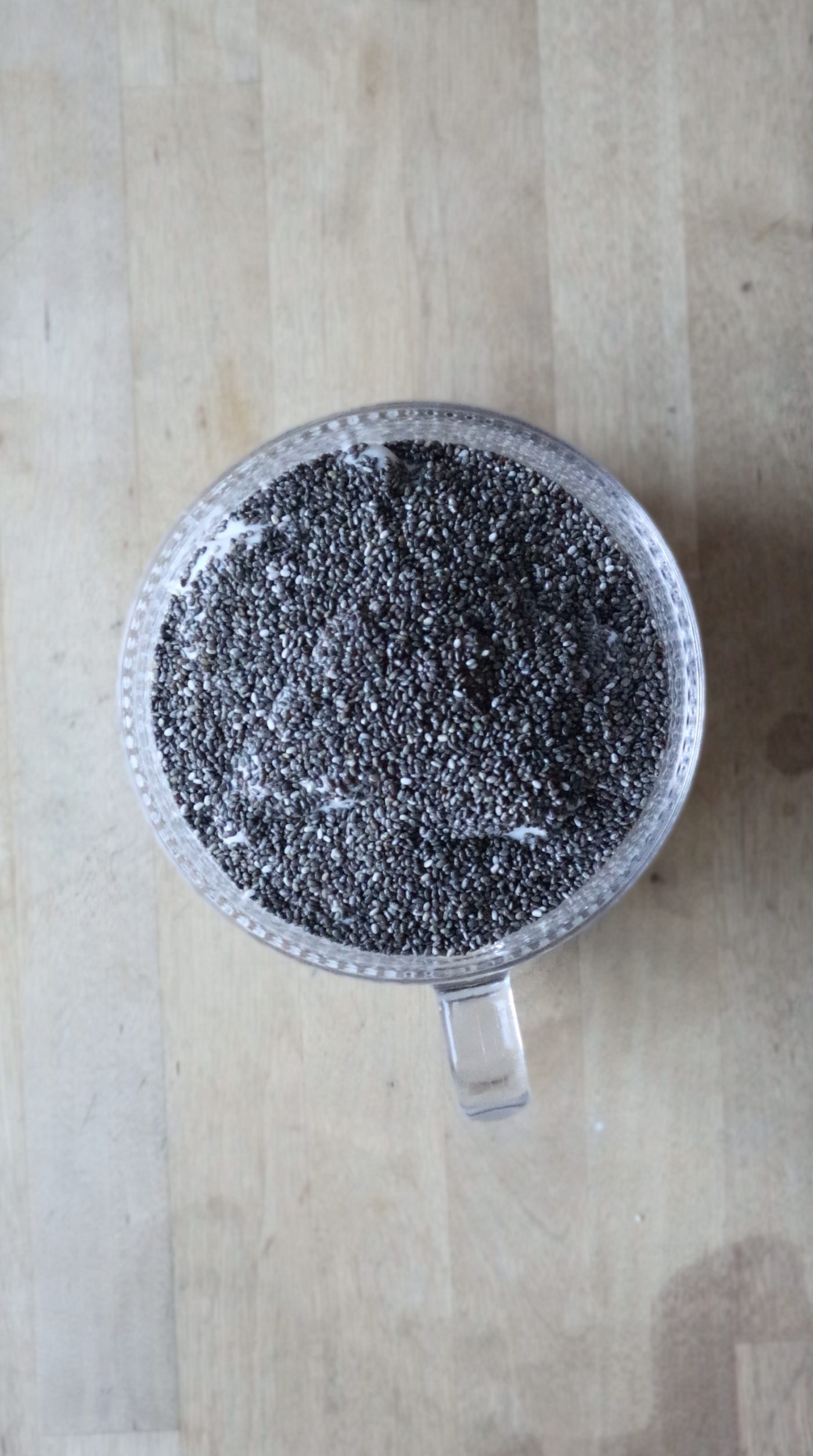 Chia seeds added on top of yogurt in a glass mug