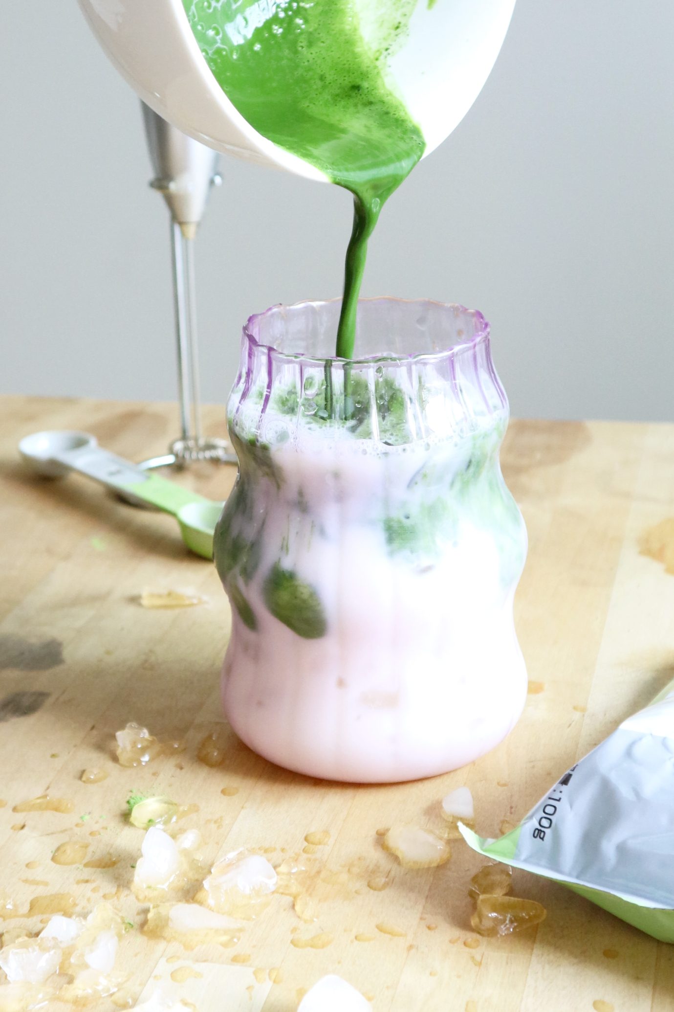 Pouring whisked matcha into a glass of milk