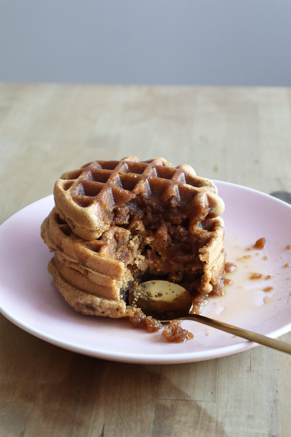 Stack of vegan waffles with maple syrup and a bite taken out